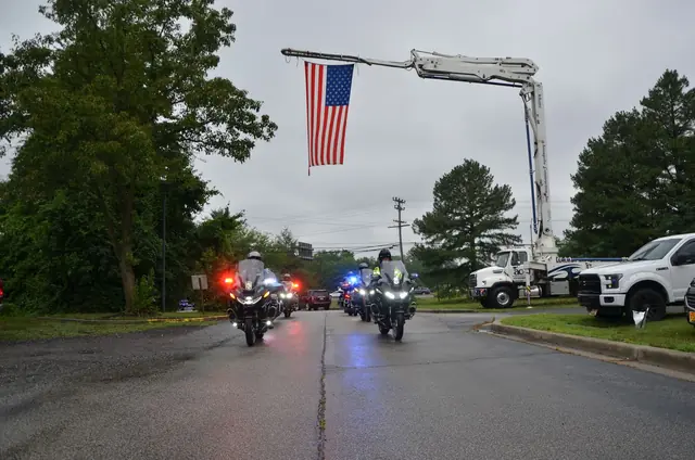 The police escort leads the ride out under the flag